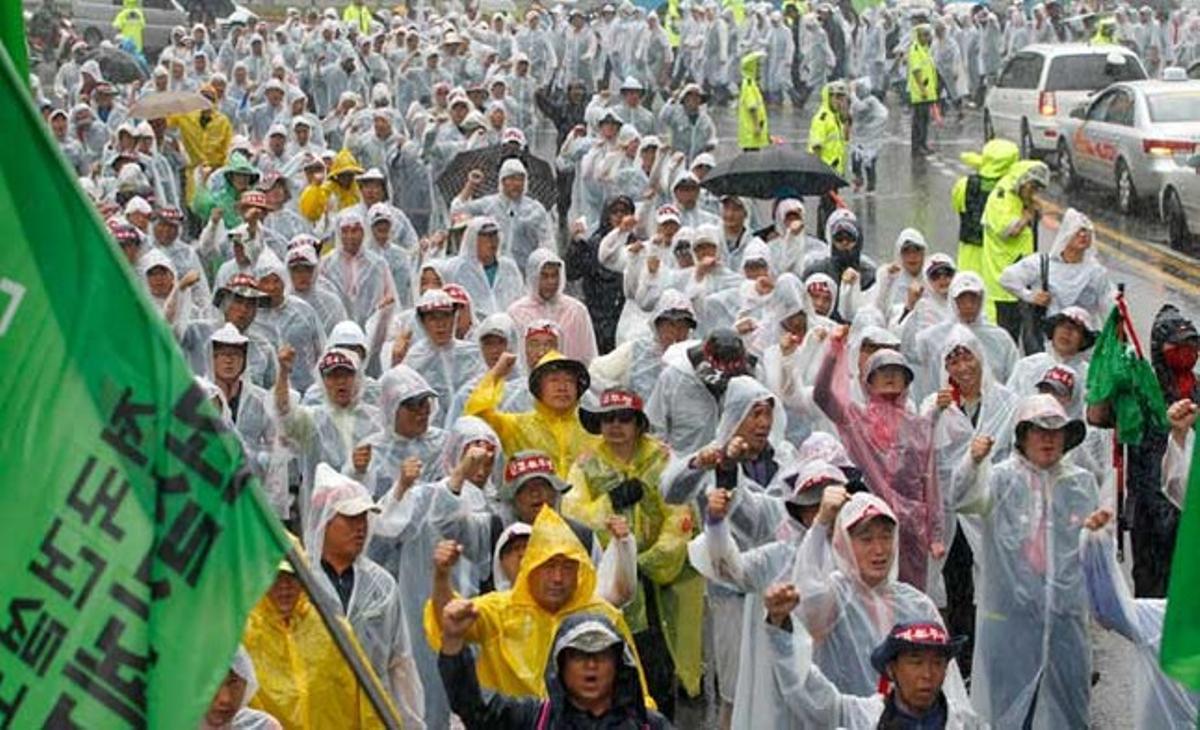 Membres de la Federació Coreana de Treballadors de la Construcció canten consignes sota la pluja durant una manifestació per exigir una millora en les seves condicions de treball a Seül. Prop de 10.000 treballadors de la construcció han participat en la protesta.