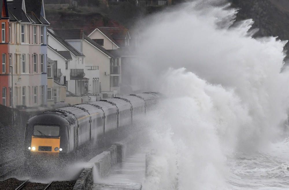Large waves crash over a train as it passes ...