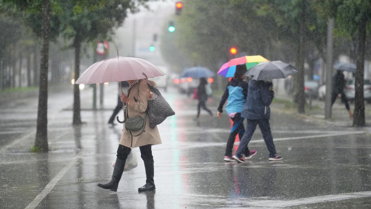 Varias personas caminando bajo la lluvia en A Coruña.