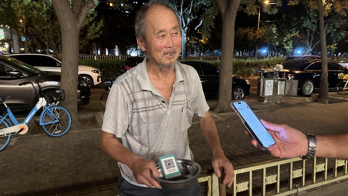 Un indigente pide caridad en la calle de Pekín con un QR, para que le hagan la transferencia directamente