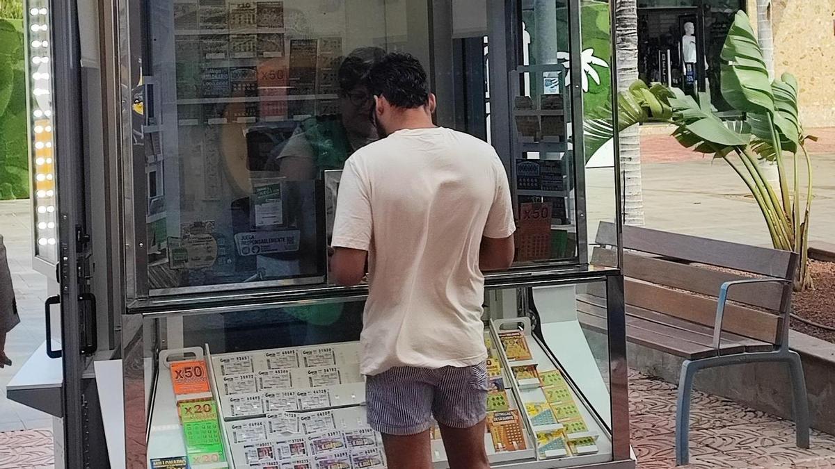 Un joven compra un cupón en un quiosco de la ONCE.