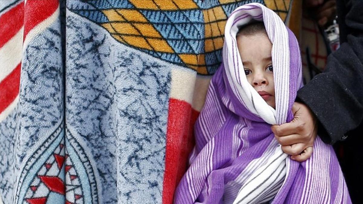 Un niño cubierto con una manta para combatir el frío en un campo de refugiados croata.