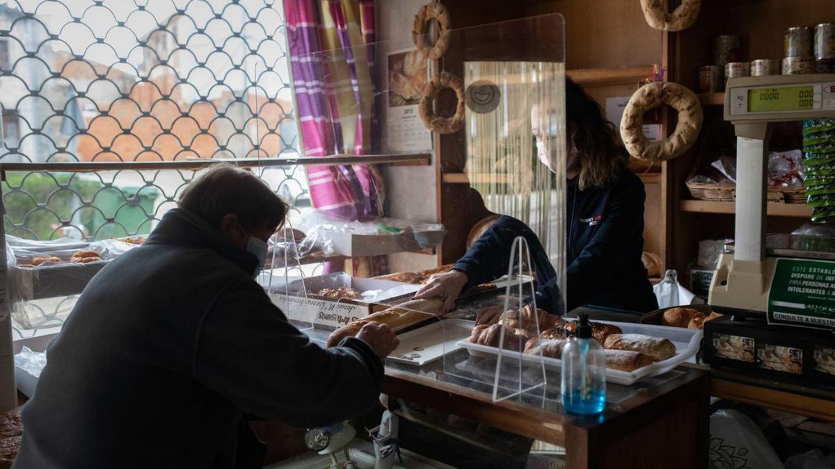 Una mujer se lleva una barra de pan en Carbajales de Alba. | Emilio Fraile