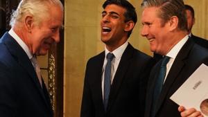 El rey Carlos conversa con el primer ministro, Rishi Sunak, y el líder laborista, Keir Starmer, durante la visita del monarca al Parlamento británico, este martes.