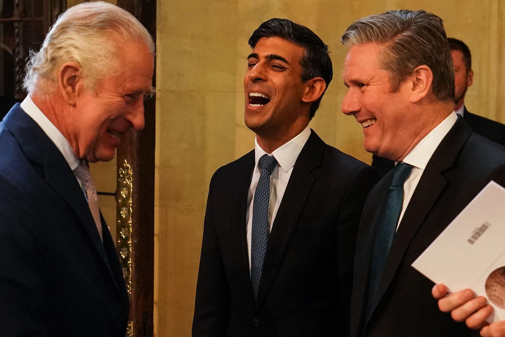 El rey Carlos conversa con el primer ministro, Rishi Sunak, y el líder laborista, Keir Starmer, durante la visita del monarca al Parlamento británico, este martes.