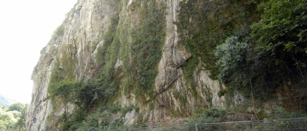 Un coche circulando junto a la cueva, cerrada con una verja metálica.