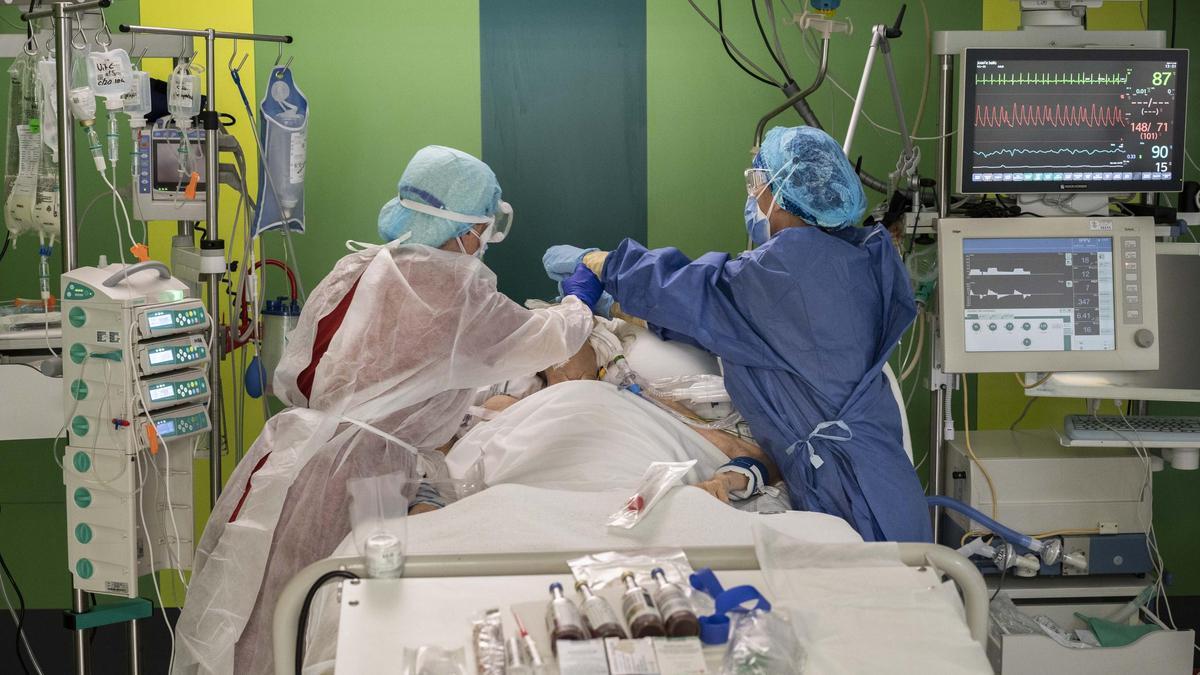 Dos sanitarios protegidos con EPI atienden a un paciente covid en la UCI del Hospital General de València.