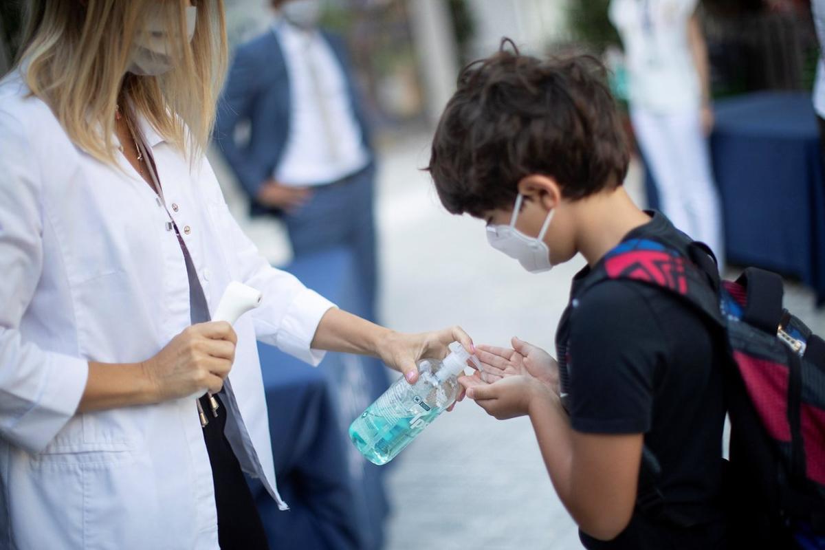 Un niño se desinfecta las manos después de que le tomen la temperatura a la entrada del colegio Un niño se desinfecta las manos después de que le tomen la temperatura a la entrada del colegio