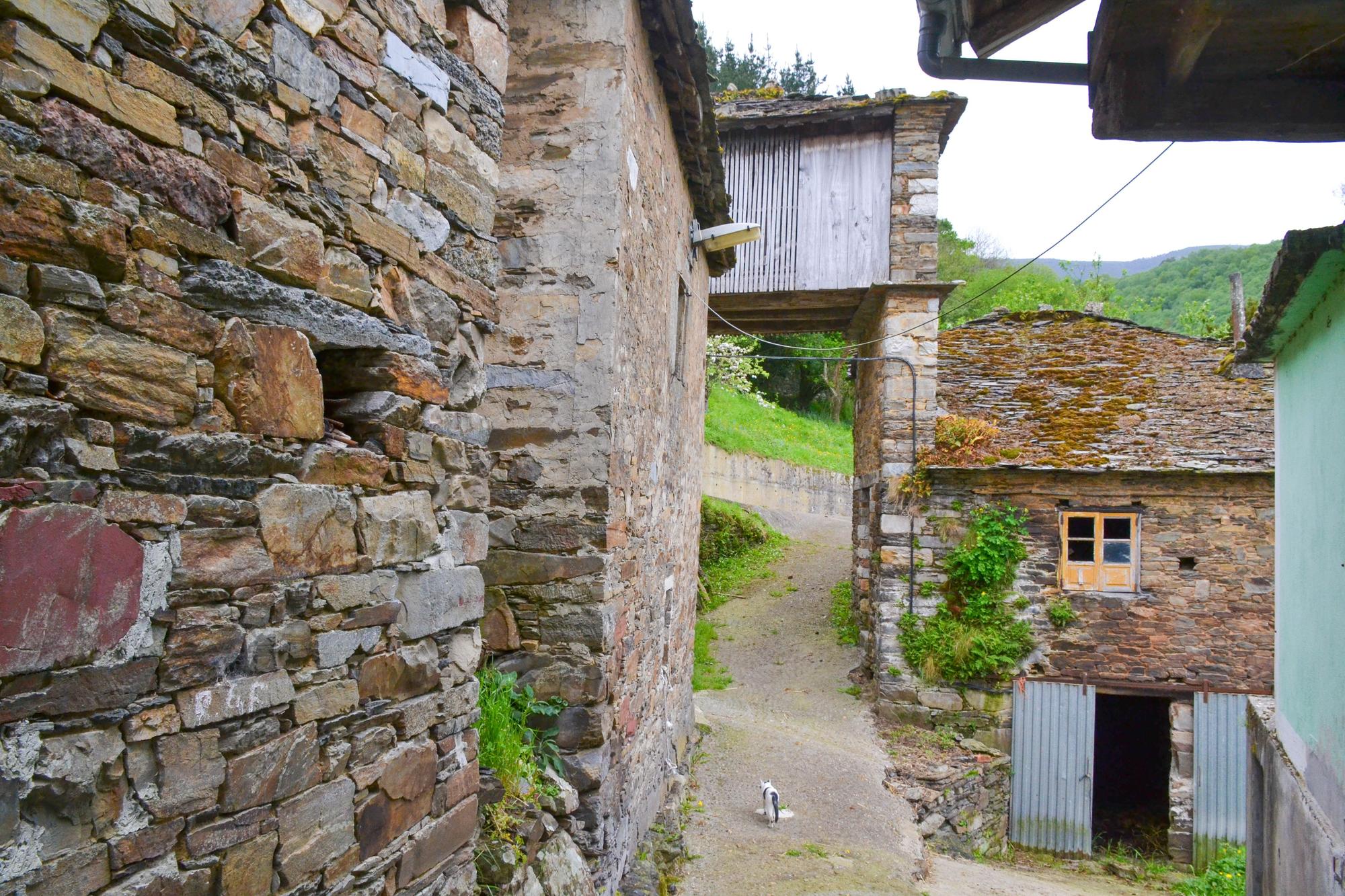 Un rincón del pueblo, con un cabazo sobre la vía, al fondo.