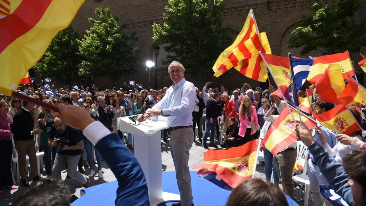 Jorge Azcón, candidato popular, entre banderas del PP, de Aragón y de España.º