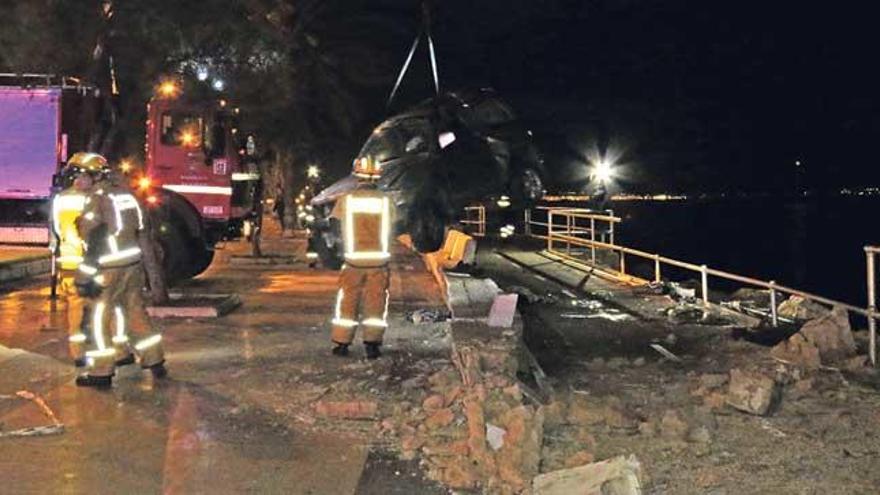 Los bomberos izan el vehículo siniestrado.