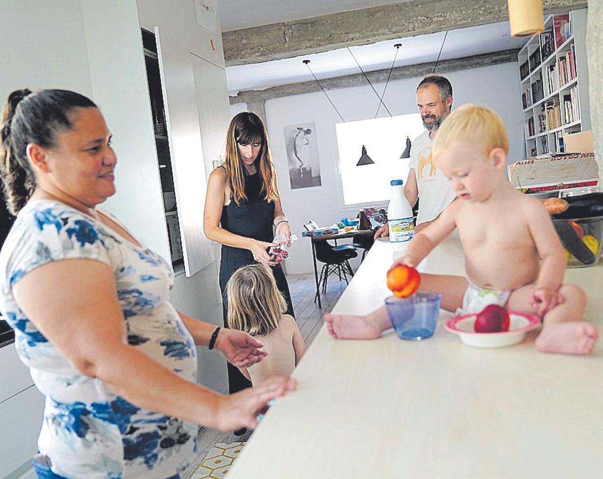 Una mujer cuida de dos niños ante la presencia de sus padres.