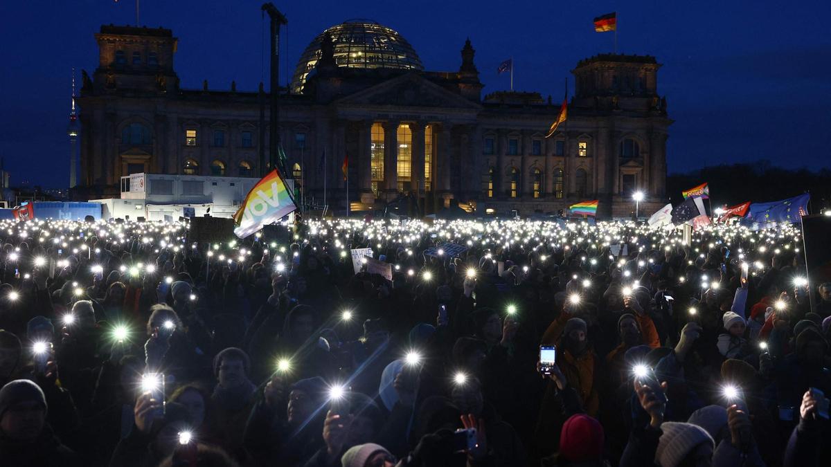 Los participantes encienden sus teléfonos móviles durante una manifestación contra el racismo y la política de extrema derecha frente al edificio del Reichstag en Berlín, el 21 de enero de 2024.