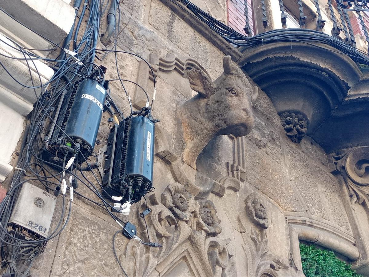 La antigua vaquería de la carretera de Sants, con la testa de vaca envuelta de cajas y cables de fibra óptica.