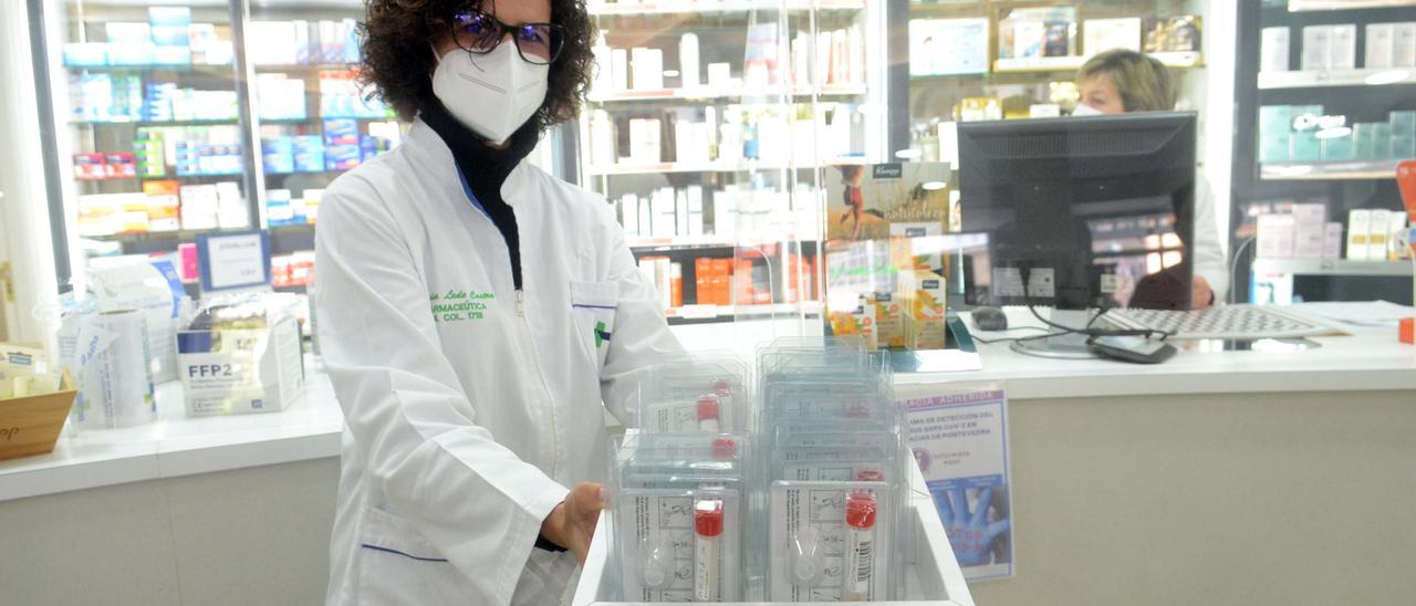 La farmacéutica María Lede muestra una caja con los botes para la recogida de muestras