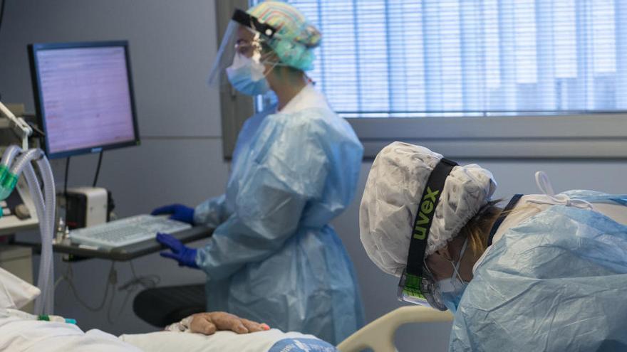 Personal sanitario atendiendo a un paciente ingresado en la UCI.