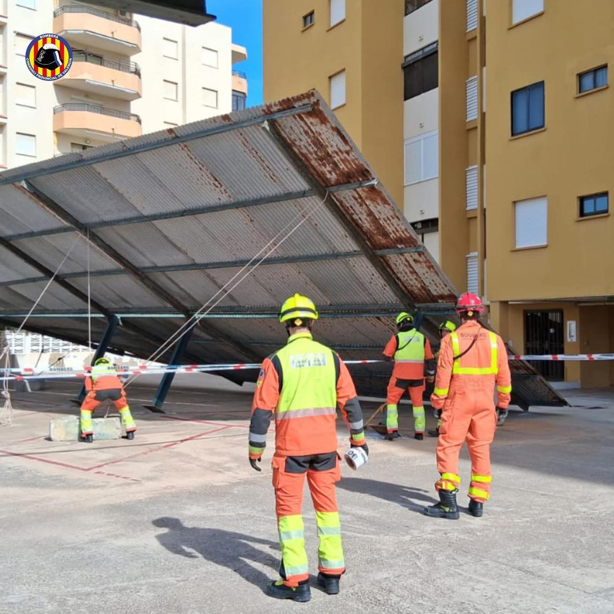 Los bomberos retiran la marquesina caída.