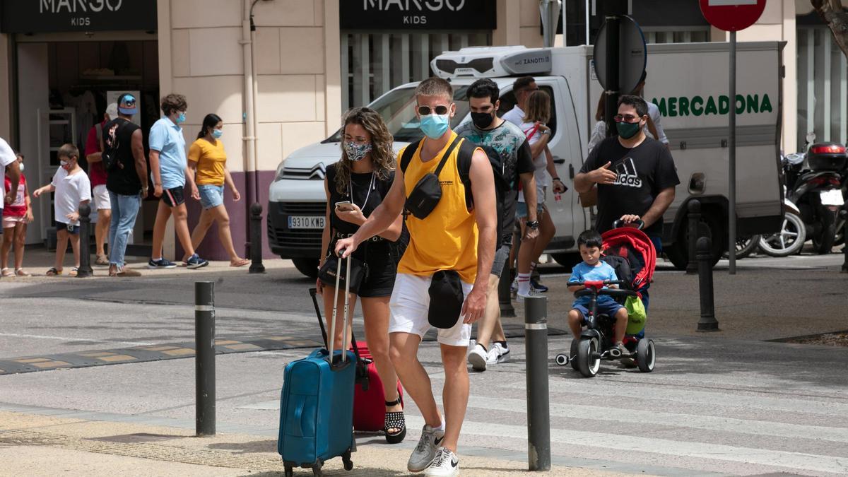 Dos turistas arrastran sus maletas en una calle de Ibiza.