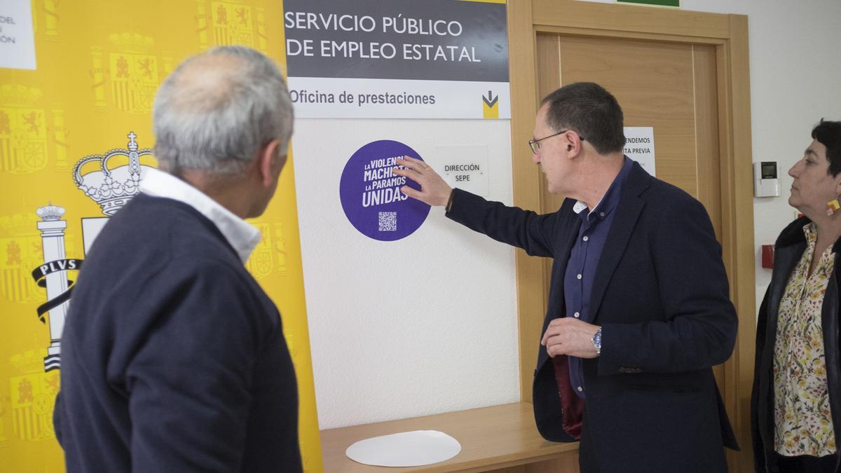 El subdelegado del Gobierno, Ángel Blanco, colocando un adhesivo del Punto Violeta en el SEPE de Benavente.