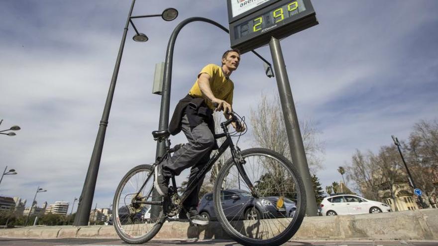 Un ciclista pasa hoy ante un termómetro a 29 grados