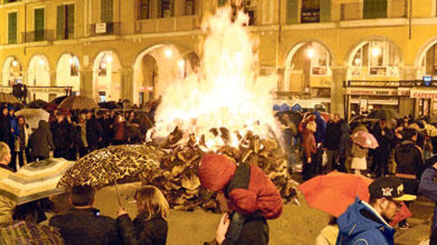 Gente con paraguas  junto al ´fogueró´ de la plaza Major.