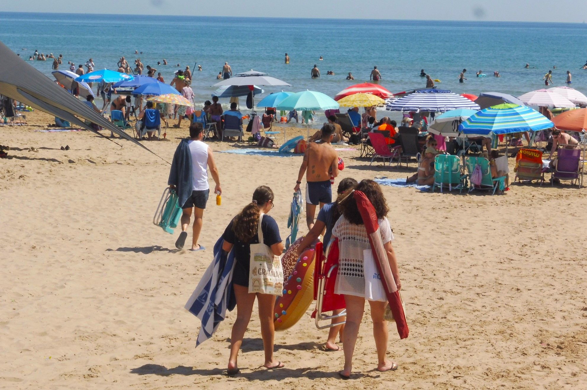 Bañistas se dirigen a la playa de Gandia, esta mañana.
