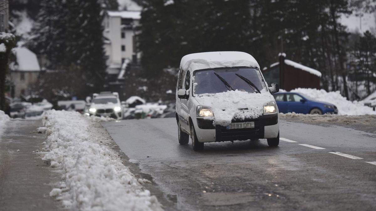 Un coche cubierto de nieve en una carretera.