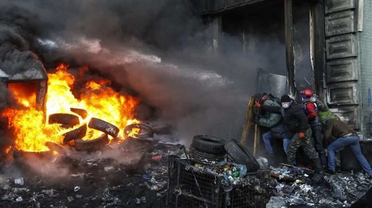Manifestants preeuropeus es posen a cobert del canó d’aigua d’un camió de bombers.