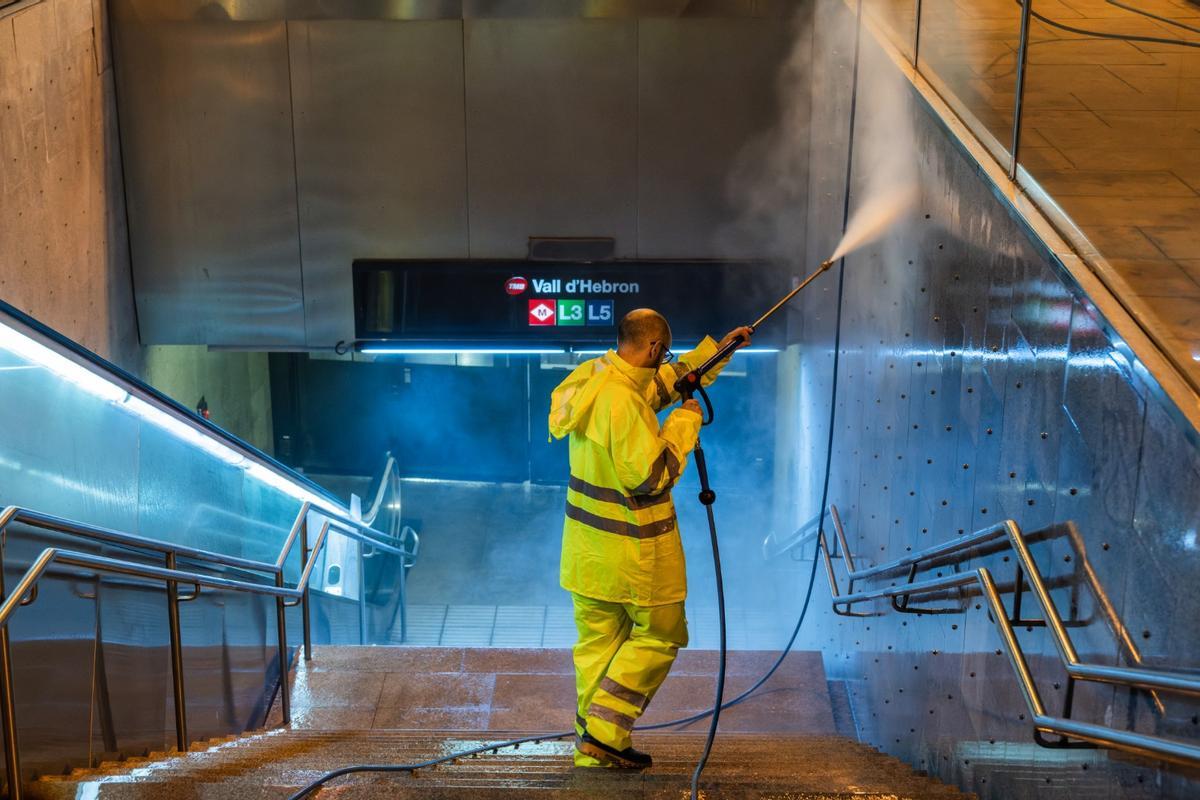 Un operario limpiando la boca de la parada de metro de Vall d'Hebron, en Barcelona.