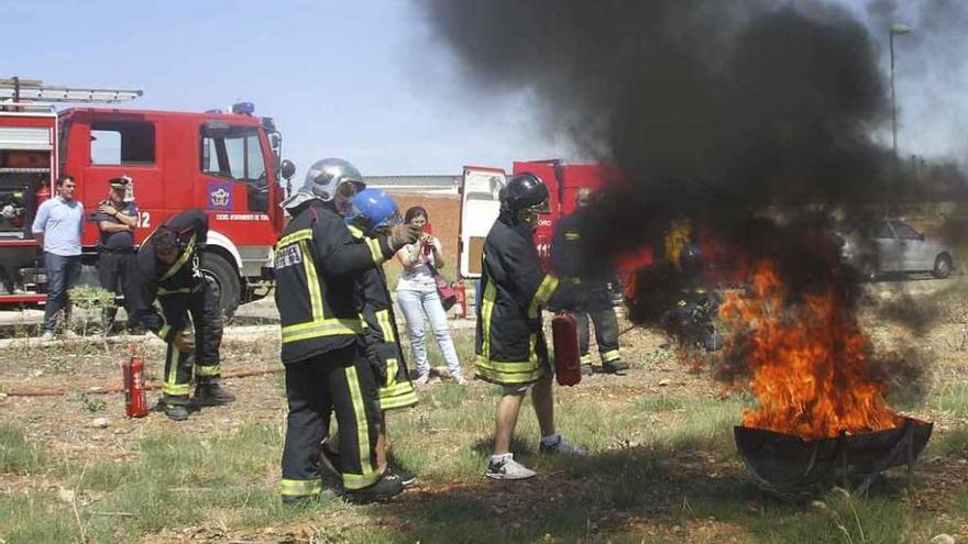 Los bomberos explican a un trabajador cómo utilizar un extintor para apagar un fuego. Foto