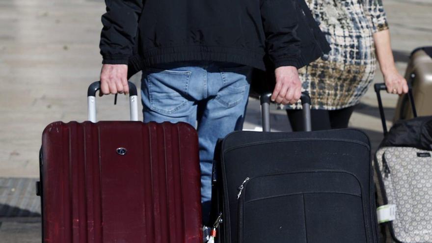 Turistes arrossegant maletes a la sortida d’un hotel.