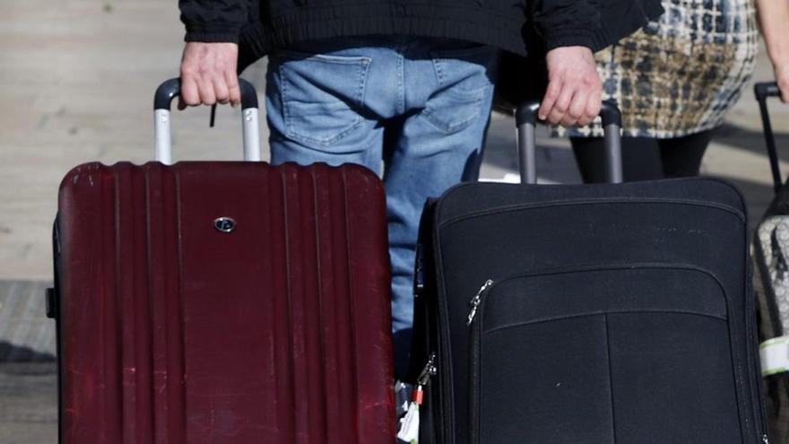 Turistes arrossegant maletes a la sortida d’un hotel | LOM