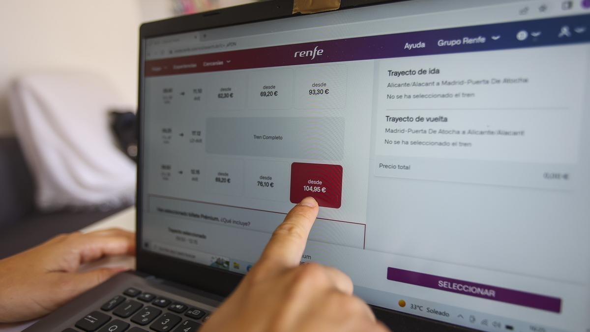 Una pasajera señala el precio de un billete del AVE entre Alicante y Madrid buscado en la web de Renfe