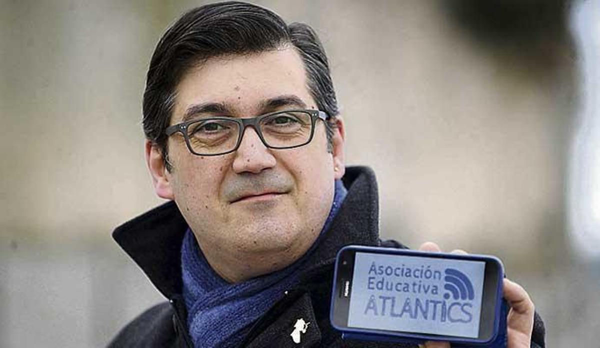 Santiago Rey, con un teléfono móvil en el que se ve el logotipo de la asociación que preside.