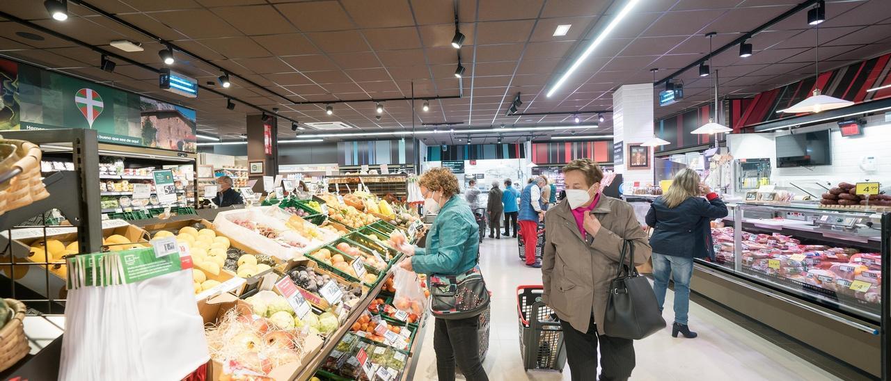 Varias personas hacen la compra en un supermercado.