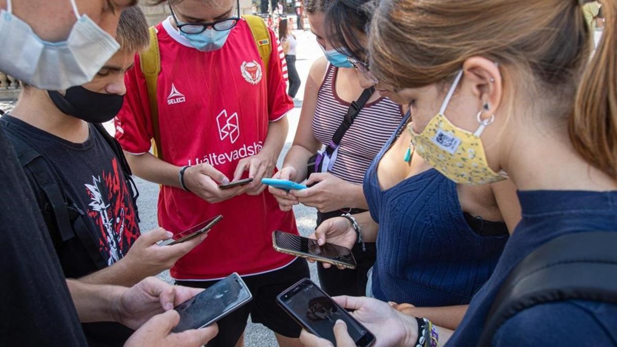 Grupo de jovenes mirando juntos sus telefonos moviles.