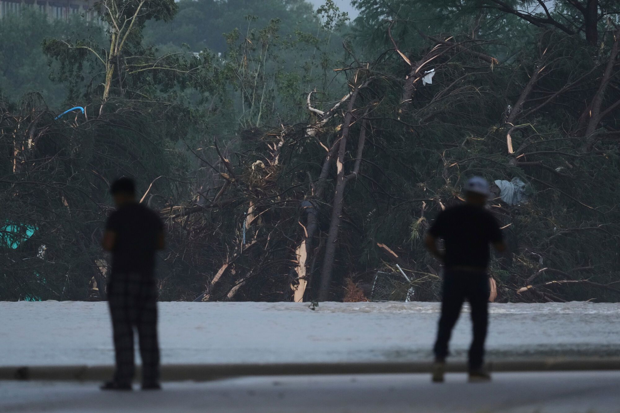 Onlookers survey damage caused along the Guadalupe River after a flash flood swept through the area, Friday, July 4, 2025, in Kerrville, Texas. (AP Photo/Eric Gay)