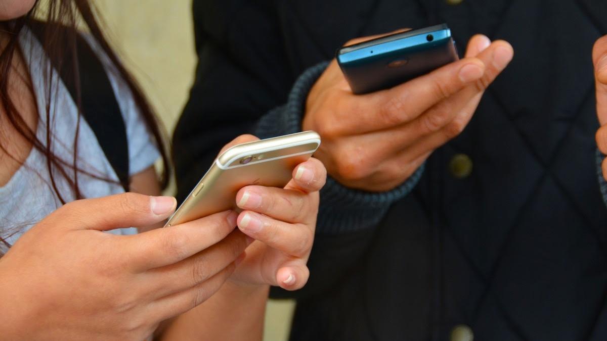 Dos personas usan teléfonos móviles.
