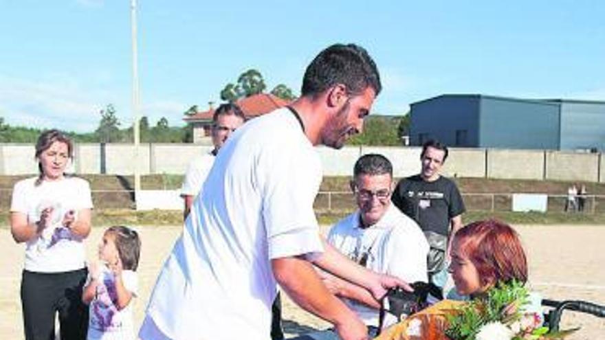 El exciclista Óscar Pereiro entrega un ramo a Yessica, junto al nadador Chano Rodríguez, ayer en Nespereira.  // Rodrigo Otero