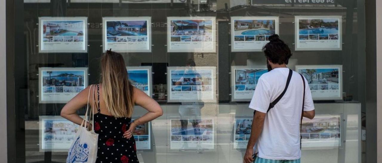 Imagen de archivo de dos personas observando anuncios en una inmobiliaria.