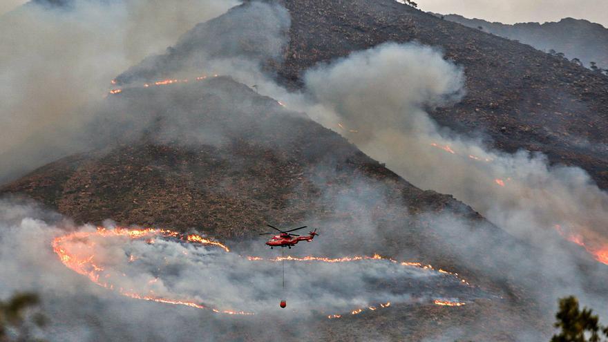 Un helicóptero, de camino a la zona incendiada para descargar agua. | ÁLEX ZEA