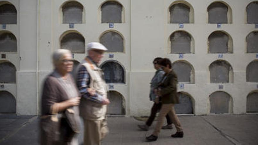 Visitantes del cementerio pasan junto a las hileras de tumbas antiguas.