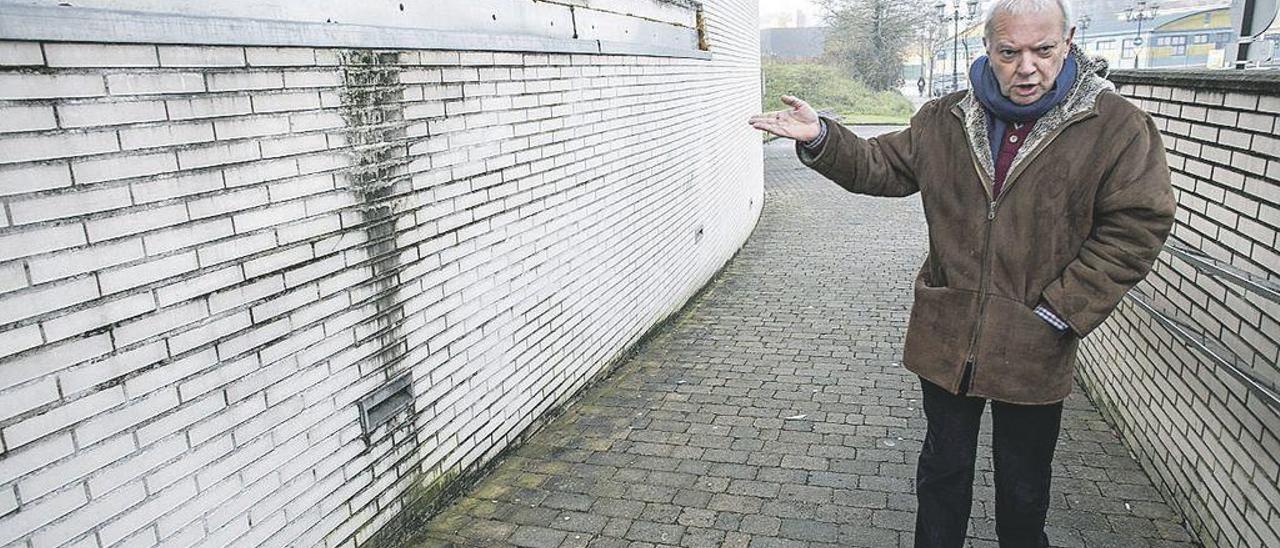 Nicanor Platero, presidente de la asociación &quot;El Conceyín&quot;, señala una de las paredes afectadas por la humedad en el exterior del centro de salud de La Corredoria.