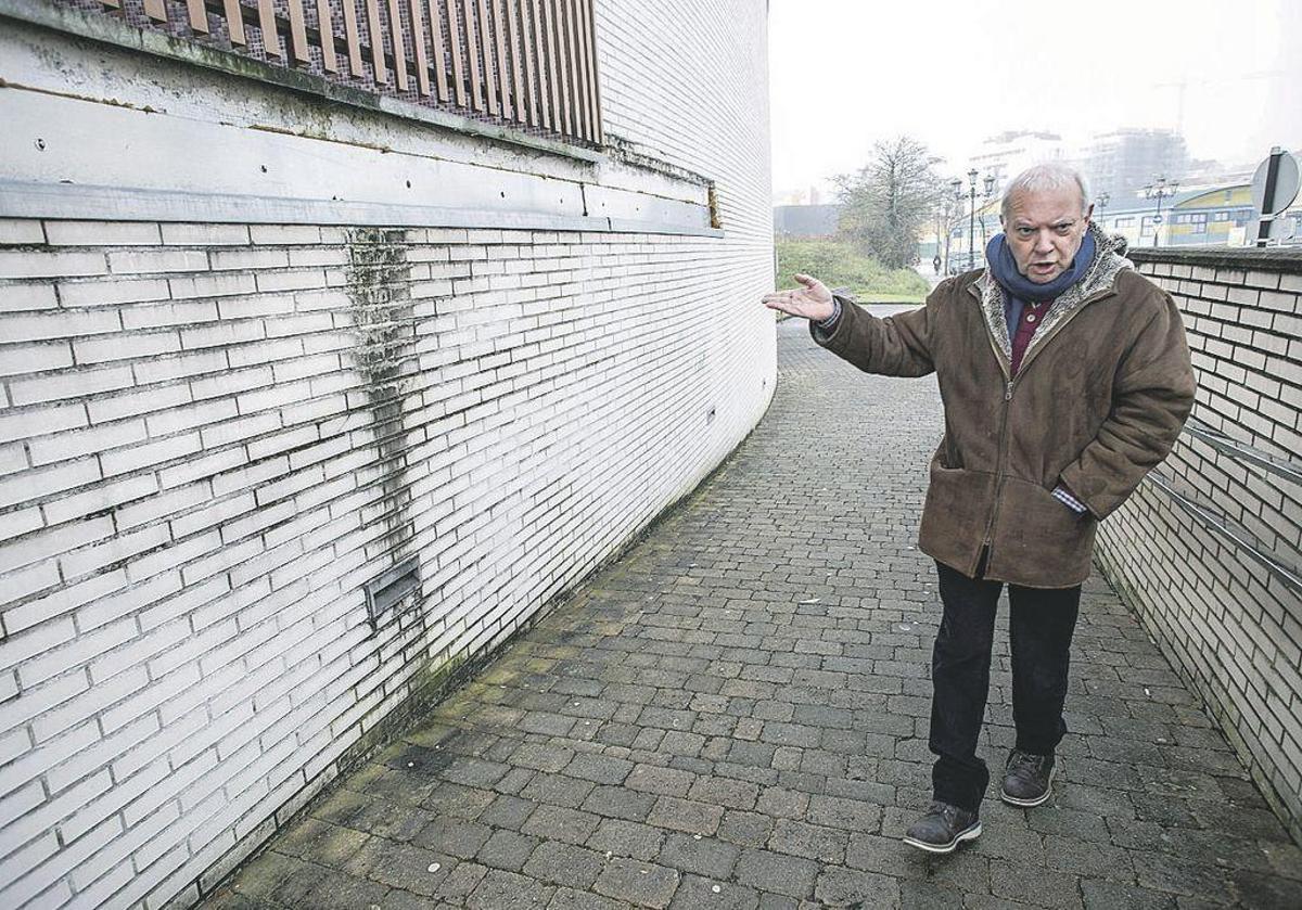 Nicanor Platero, presidente de la asociación "El Conceyín", señala una de las paredes afectadas por la humedad en el exterior del centro de salud de La Corredoria.
