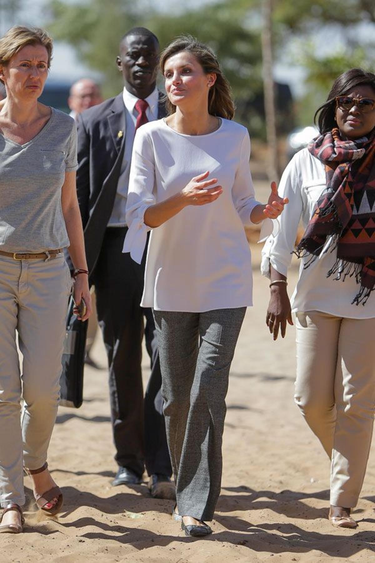 Letizia Ortiz con blusa blanca y pantalones anchos grises en África y bailarinas