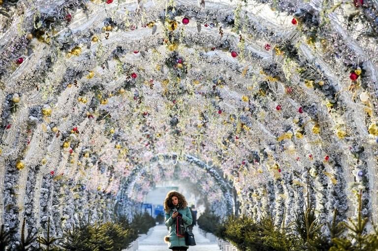 Una mujer camina en un túnel decorado con luces festivas en el centro de Moscú, en Rusia. 17 de diciembre de 2018. Kirill KUDRYAVTSEV / AFP