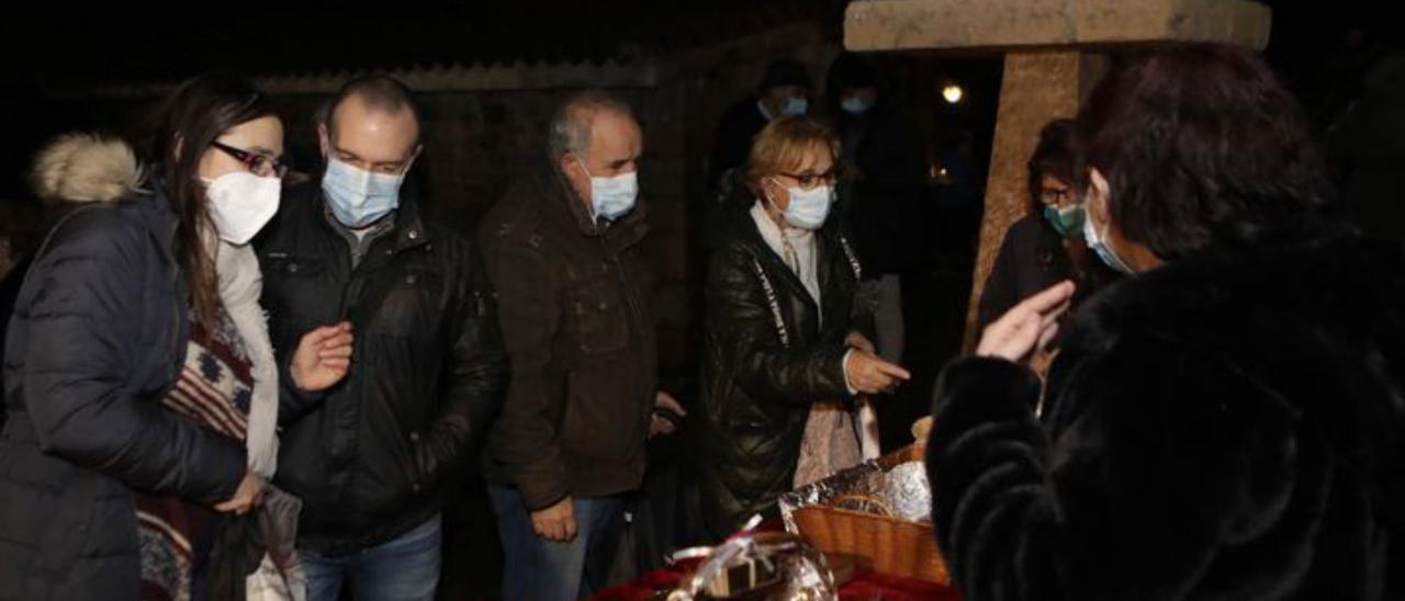 Arriba, vecinos esperando a la inauguración del belén de Bueño. En los círculos, a la izquierda, vecinos del pueblo de Ribera de Arriba, comprando en el mercadillo solidario; a la derecha, vecinos admirando el nacimiento en la capilla de la parroquia.   Fernando Rodríguez