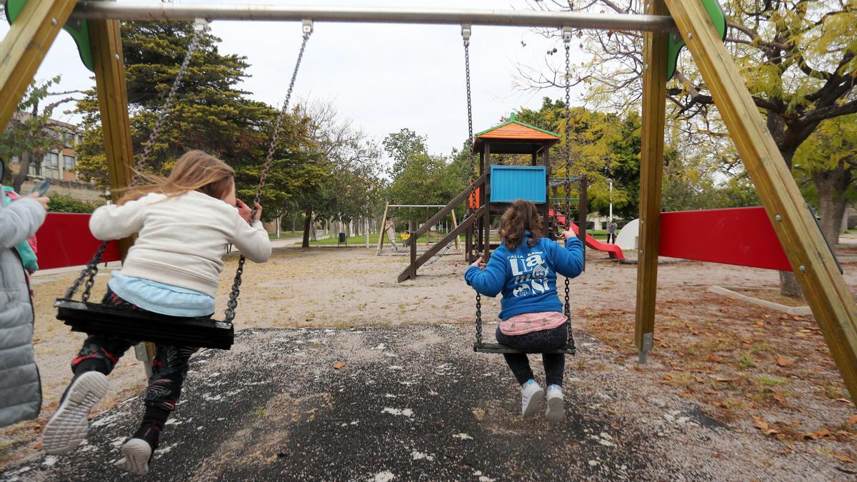 Dos niñas juegan en un columpio del parque de València.