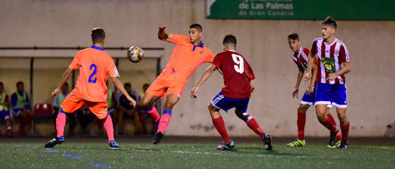La defensa del filial amarillo saca el balón con la presión de los delanteros del Atlético Gran Canaria.