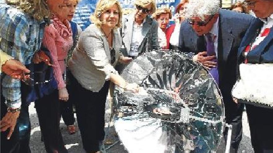 demostración. La concejala M.ª Àngels Ramón-Llin muestra a los asistentes las longanizas cocinadas por el sol.